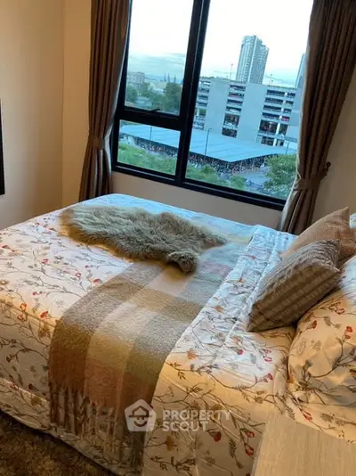 Cozy bedroom with city view, featuring floral bedding and large window for natural light.