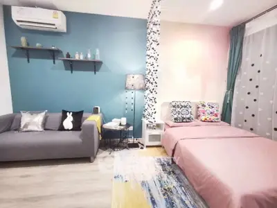 Charming bedroom with modern decor, featuring a cozy bed, stylish sofa, and vibrant accent wall.
