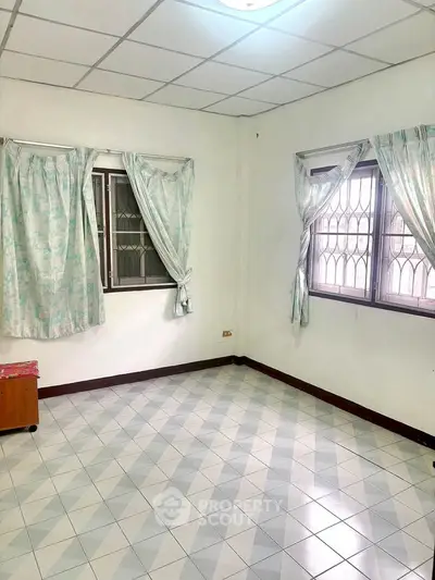 Spacious empty room with tiled floor and natural light from windows