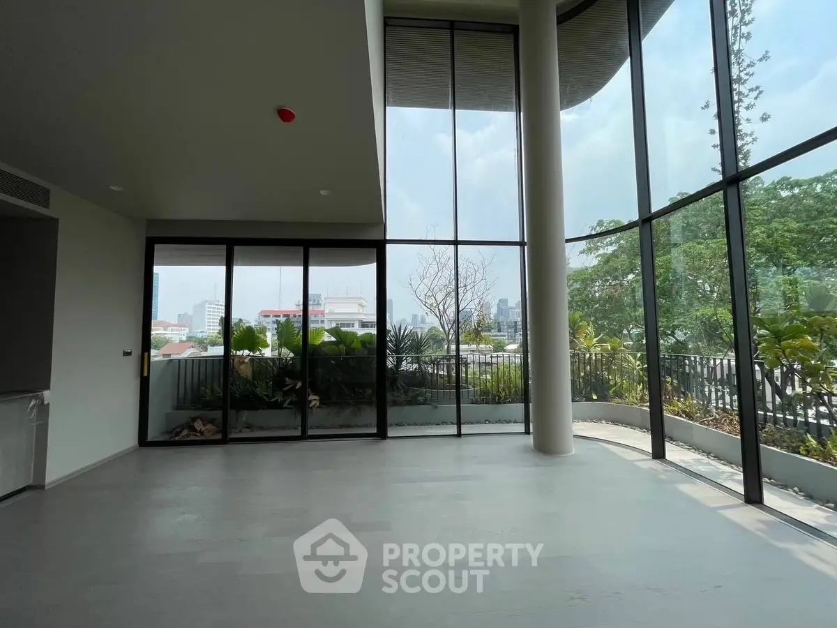 Spacious modern living room with floor-to-ceiling windows offering panoramic city views.