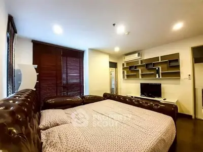 Spacious bedroom with modern decor and cozy lighting, featuring a large bed and stylish shelving.
