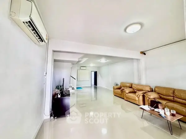 Spacious living room with modern leather sofas and sleek air conditioning unit.