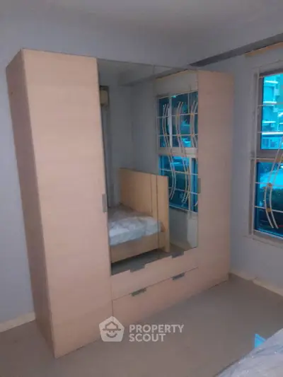 Spacious bedroom with modern wardrobe and large windows for natural light.