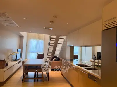 Modern open-plan kitchen and living area with stylish decor and staircase