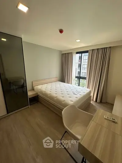 Modern bedroom with large window and stylish furniture in a bright apartment.