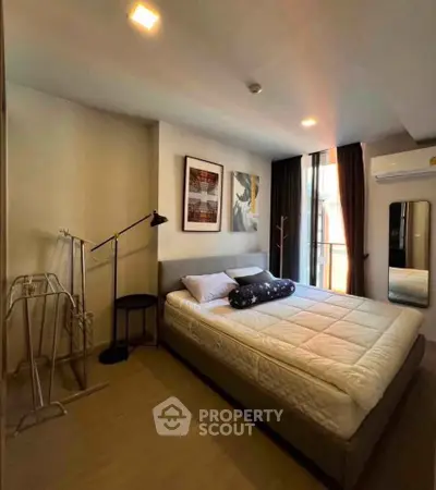 Modern bedroom with stylish decor and ample natural light, featuring a cozy bed and contemporary artwork.