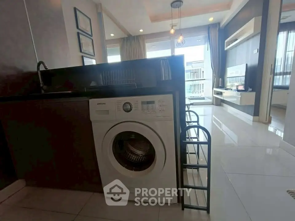 Modern living room with washing machine and stylish decor in open layout apartment.