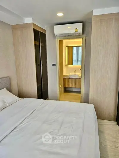 Modern bedroom with ensuite bathroom and air conditioning in stylish apartment.