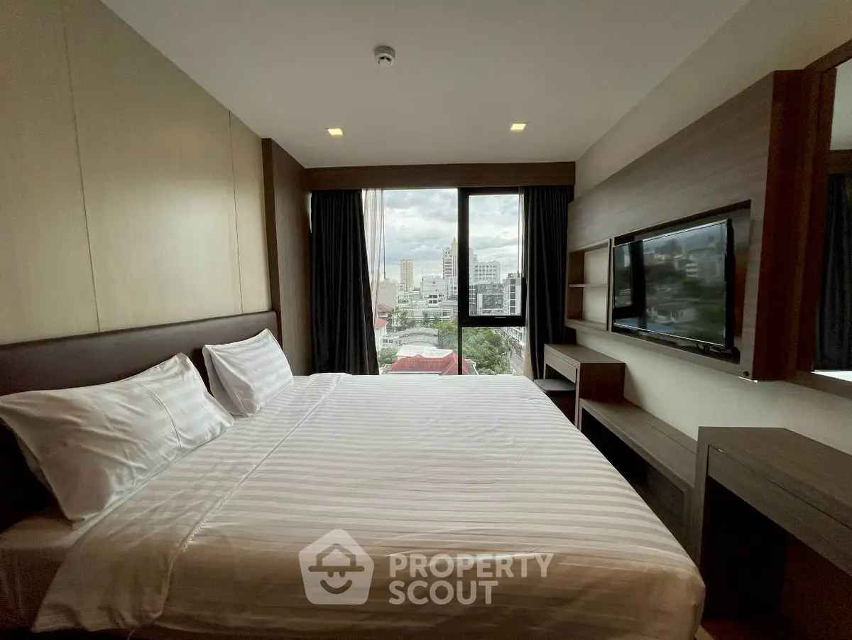 Spacious bedroom with large window offering city view and modern amenities.