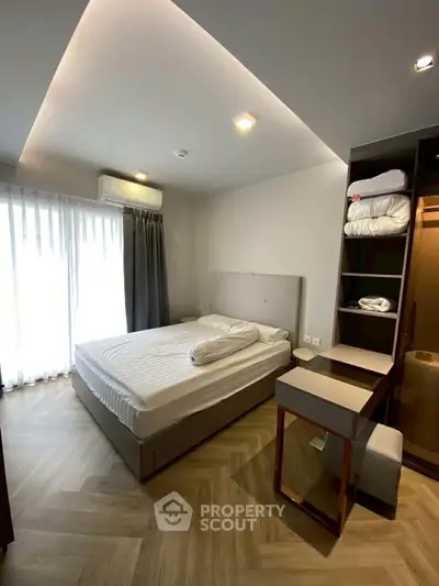 Modern bedroom with stylish decor and ample natural light, featuring a comfortable bed and built-in storage.