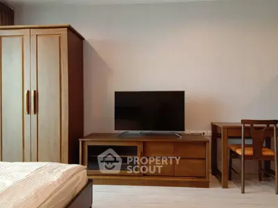 Cozy bedroom with wooden furniture and modern TV setup, perfect for relaxation.