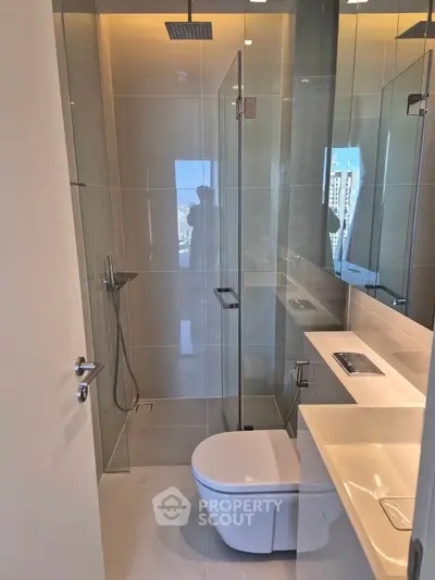 Modern bathroom with sleek glass shower and contemporary fixtures in luxury apartment.