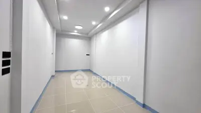 Spacious empty room with modern lighting and tiled flooring, ideal for customization.