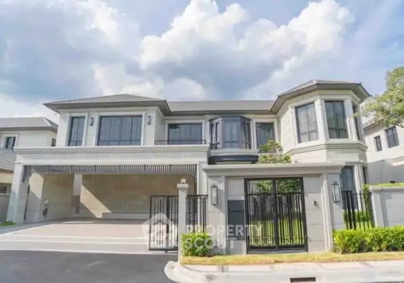 Luxurious modern two-story house with spacious driveway and elegant facade under a clear blue sky.