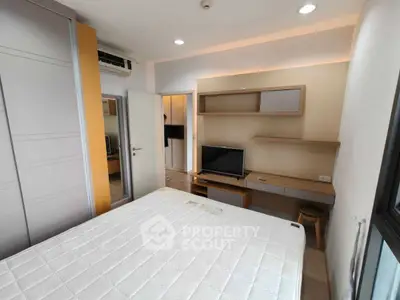 Modern bedroom with built-in wardrobe and TV, featuring sleek design and ample natural light.
