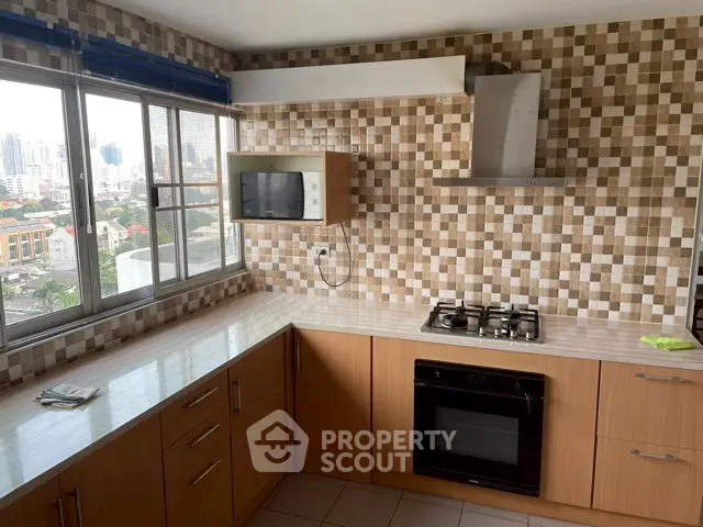 Modern kitchen with city view, featuring gas stove and stylish tile backsplash.