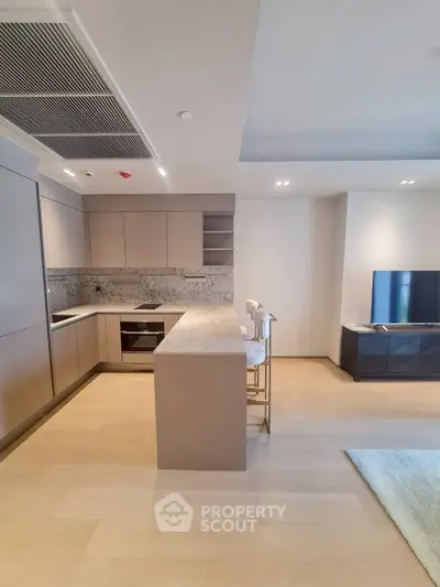 Modern open-layout kitchen with sleek cabinetry and marble countertops in a stylish apartment.
