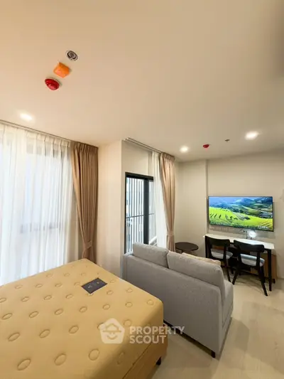 Modern studio apartment with cozy living area and scenic view from balcony.