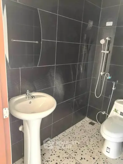 Modern bathroom with sleek black tiles and contemporary fixtures.