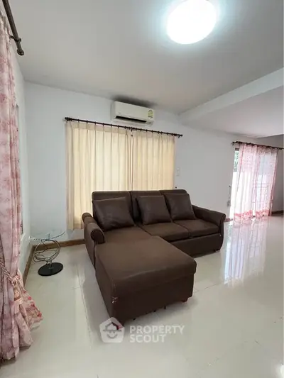 Spacious living room with modern brown sofa and natural light