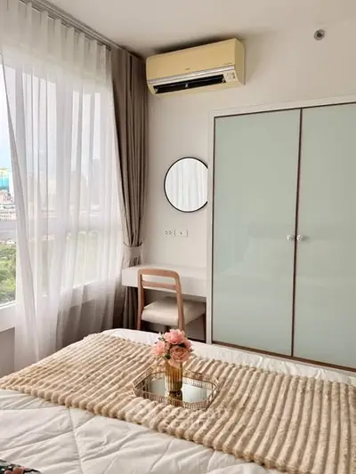 Cozy bedroom with modern decor, featuring a large window and stylish furnishings.