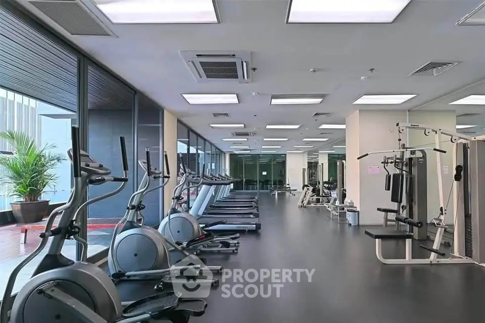 Spacious modern gym with state-of-the-art equipment and large windows for natural light.