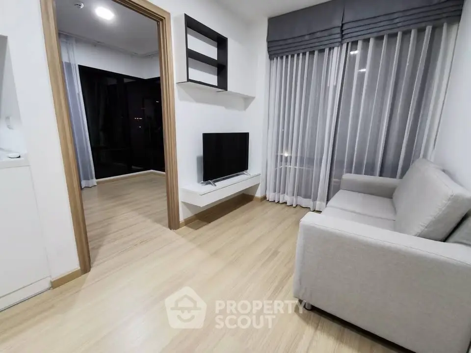Modern living room with sleek design and cozy ambiance, featuring a wall-mounted TV and elegant curtains.