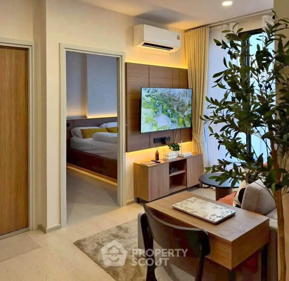 Modern living room with stylish decor and view into cozy bedroom, featuring air conditioning and natural light.