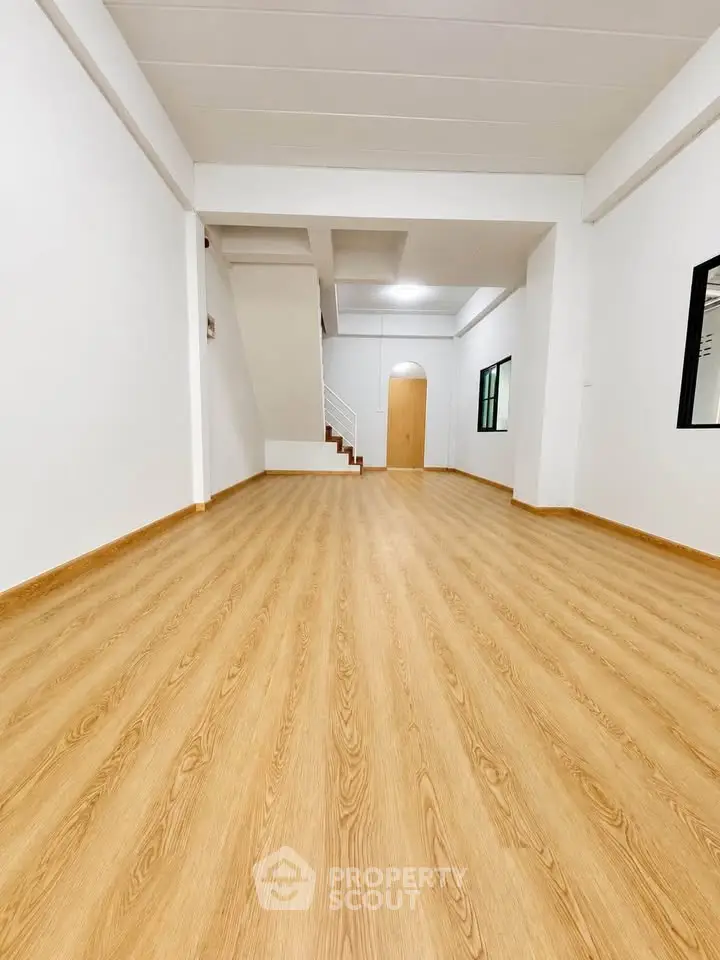 Spacious open-plan living area with wooden flooring and modern staircase.