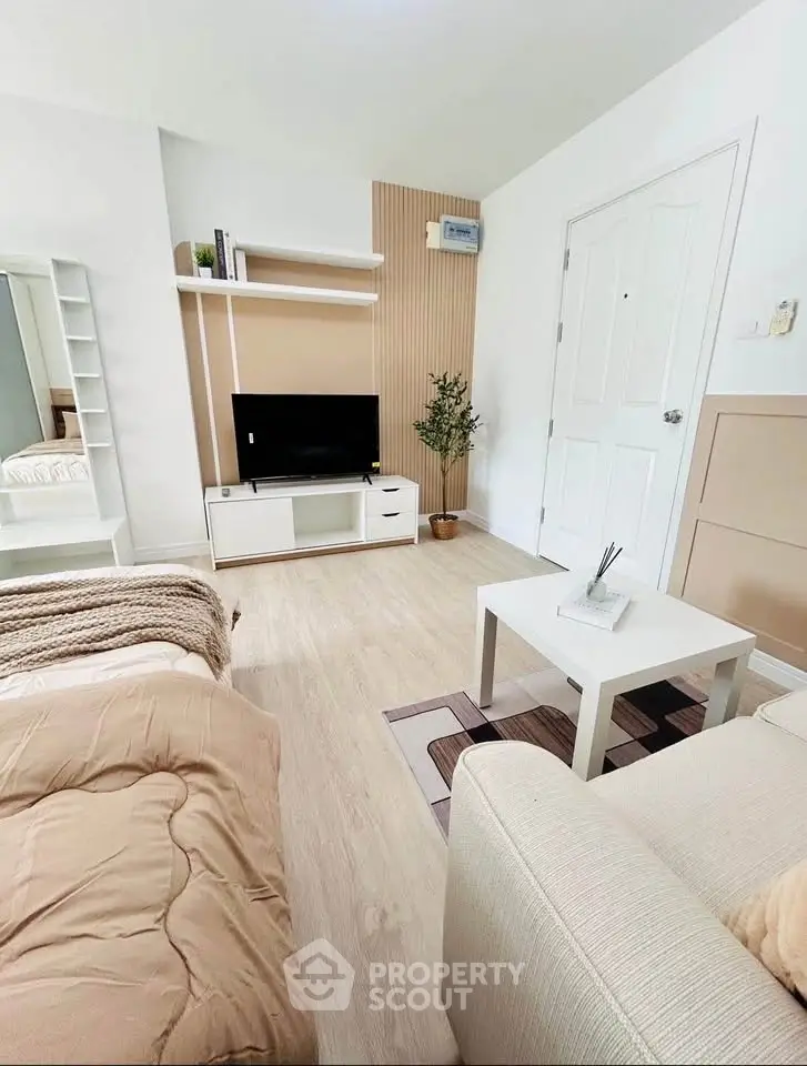 Modern living room with stylish decor and cozy ambiance, featuring a TV and comfortable seating.