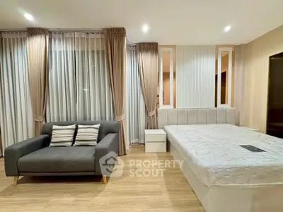 Modern bedroom with stylish decor, featuring a cozy sofa and elegant curtains, perfect for relaxation.