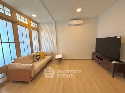 Modern living room with wooden flooring, stylish sofa, and large TV setup.