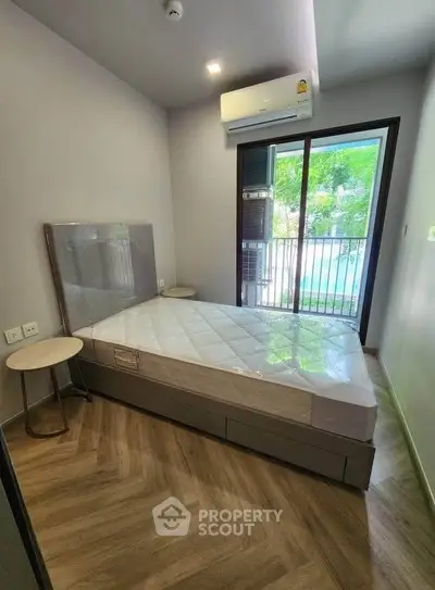 Modern bedroom with air conditioning and balcony view, featuring a new mattress and parquet flooring.
