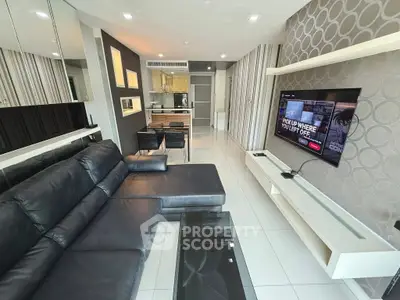 Modern living room with sleek design, black leather sofa, wall-mounted TV, and open kitchen layout.