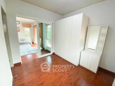 Spacious bedroom with wooden flooring and modern white furniture