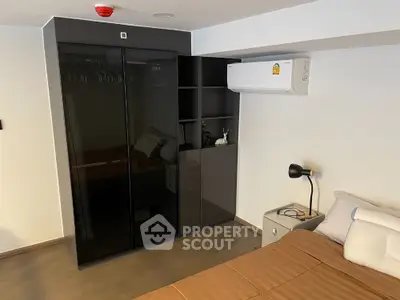 Modern bedroom with sleek black wardrobe and air conditioning unit