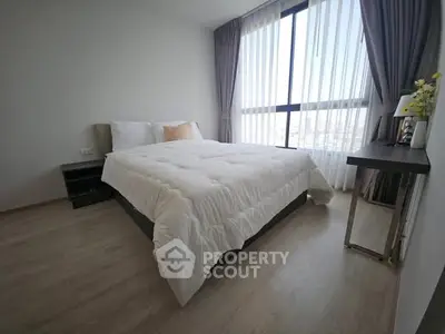 Modern bedroom with large window and elegant decor in a bright apartment.