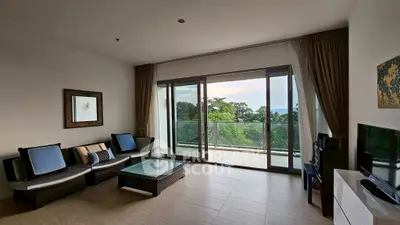 Spacious living room with large windows and balcony offering stunning views of lush greenery.