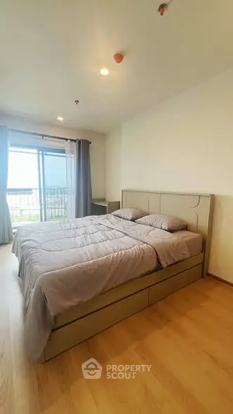 Spacious bedroom with large window and modern decor in a cozy apartment.