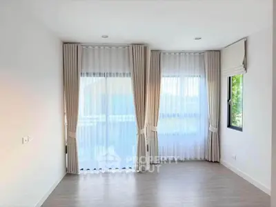 Bright and airy room with large windows and elegant curtains, perfect for a cozy living space.