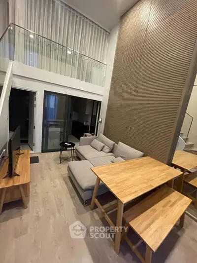 Modern loft-style living room with high ceilings and stylish wooden furniture.