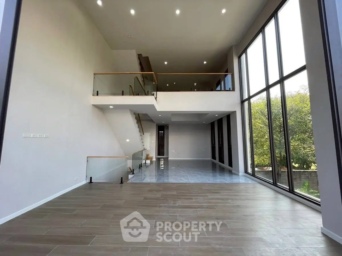 Stunning modern living room with high ceilings and expansive windows offering natural light and garden views.
