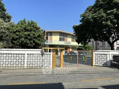 Charming two-story house with gated entrance and lush greenery, perfect for family living.