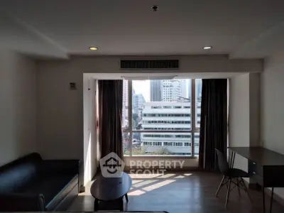 Modern living room with city view, featuring sleek furniture and large windows for natural light.
