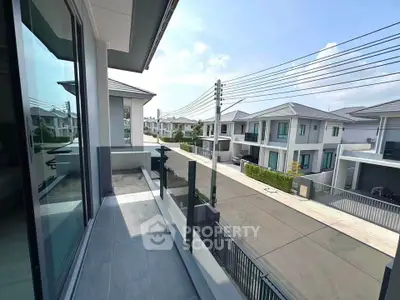 Modern residential neighborhood view from a sleek balcony with glass railing, showcasing contemporary architecture.