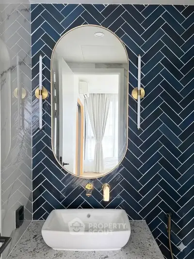 Modern bathroom with stylish herringbone tile, elegant oval mirror, and sleek fixtures.
