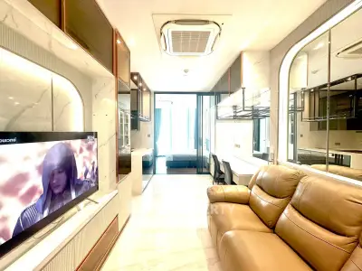 Luxurious modern living room with leather sofa and large TV, featuring elegant marble walls and ample natural light.