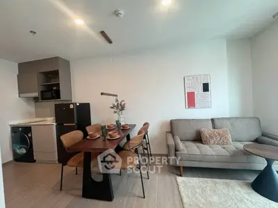 Modern living room with dining area, stylish furniture, and open kitchen layout in a cozy apartment.