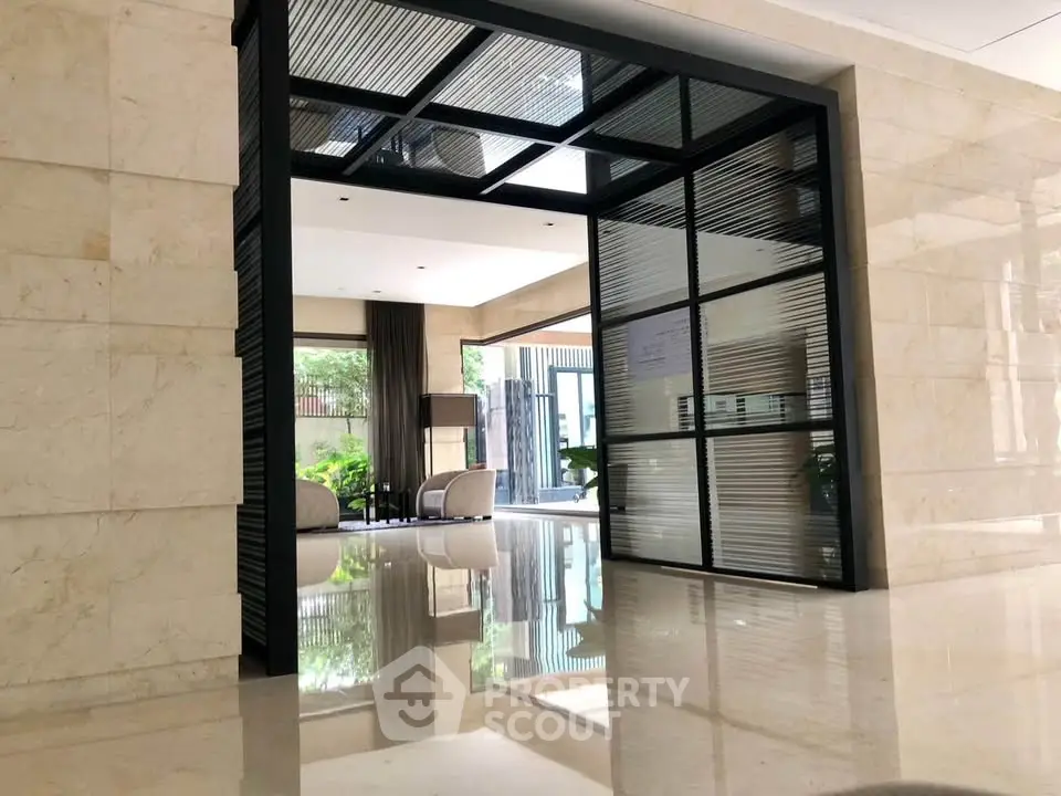 Luxurious modern building entrance with sleek glass doors and polished marble floors.