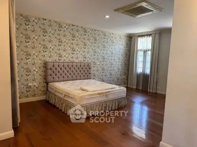 Spacious bedroom with elegant floral wallpaper and hardwood floors